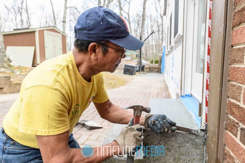 Ricardo finishing a concrete step outside a door ©TimeLine Media